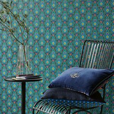 a chair and table with flowers in a vase next to a wallpapered wall