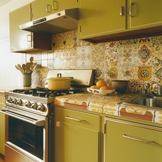 a kitchen with yellow cabinets and an oven in the center, surrounded by utensils