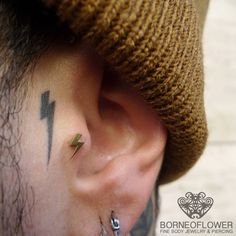 a person with a small tattoo on their left side behind the ear, wearing a hat