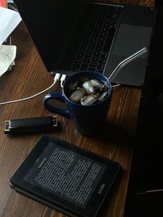 an open laptop computer sitting on top of a wooden desk next to a cup of coffee