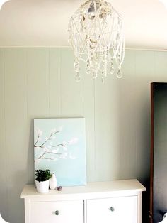 a chandelier hanging from the ceiling over a dresser