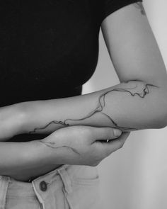 a woman's arm with a tattoo on it that is shaped like a wave