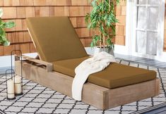 a brown chaise lounger sitting on top of a rug next to a potted plant