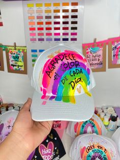 a person holding up a hat that has been decorated with rainbows and words on it