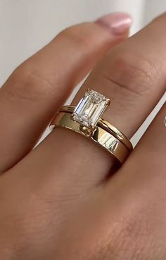 a woman's hand with two gold rings and an emerald ring on top of her finger