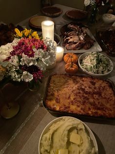 a table full of food with candles and flowers on the table in front of it