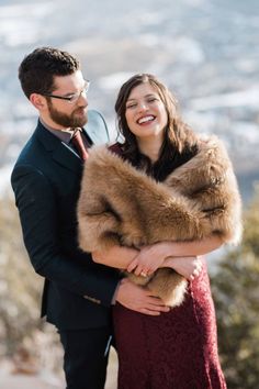 a man and woman standing next to each other in front of the camera with their arms around each other