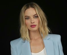 a woman with blonde hair wearing a blue blazer and white shirt, looking at the camera