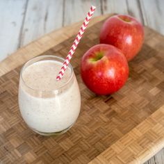 two apples sitting on a cutting board next to a glass of milk and an apple