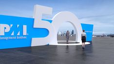 two people standing in front of a sign that says pfi management institute and the number fifty five