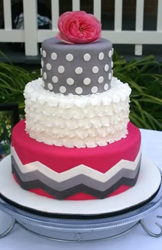 a three tiered cake with white and pink frosting