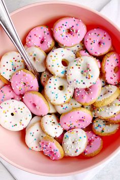 a bowl full of pink and white donuts with sprinkles