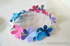 a paper flower headband with glitter flowers and butterflies on the side, sitting on a table