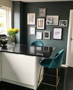 a kitchen with black counter tops and blue chairs in front of a window filled with pictures