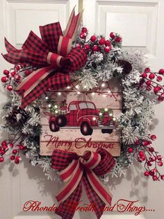 a red and white christmas wreath with an old fashioned truck on it, hanging from the front door