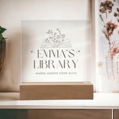 there is a glass sign that says, emma's library where words come alive