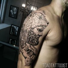 a man's arm with a lion tattoo on it and flowers in his hair