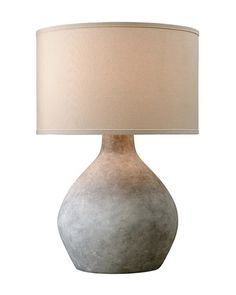 a lamp that is on top of a white surface with a beige shade over it