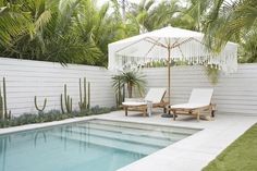 two lounge chairs next to a pool with an umbrella