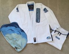 a white karate suit sitting on top of a floor next to a blue and white mitt