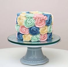 a multicolored cake with frosting roses on top