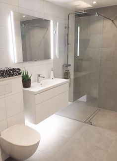 a bathroom with a toilet, sink, and shower stall in white tiled flooring