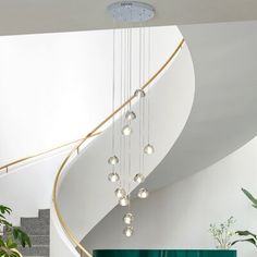 a spiral staircase in a modern home with green curtains and potted plants on the side