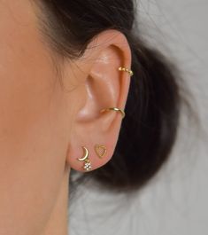 a close up of a person with ear piercings on their ears and wearing gold jewelry