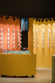 a yellow counter in front of wooden wall with pictures on it and lights hanging from the ceiling