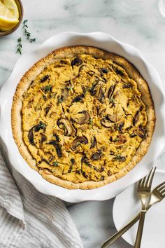 an overhead view of a quiche in a white pie dish on a marble table