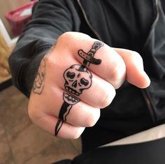 a person with tattoos on their fingers holding a knife