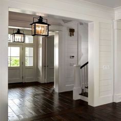 an empty entryway with two lanterns hanging from the ceiling and wood floors in front of it