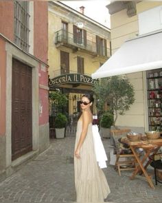 a woman in a white dress is walking down the street