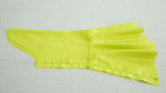 a piece of yellow material with pleating on it's side, laying on a white surface