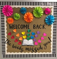 a bulletin board with colorful paper flowers and an open book on it that says, welcome back the books missed you