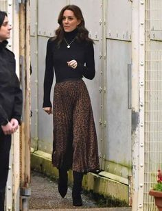 the woman is wearing a black turtle neck sweater and leopard print high - waisted skirt