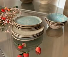 a glass table topped with plates and bowls filled with strawberries