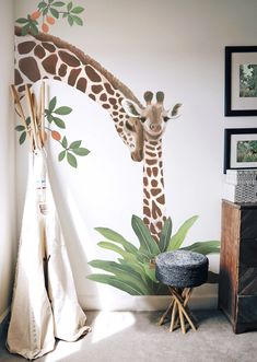 a giraffe is standing in front of a wall mural