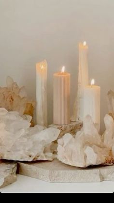 some white candles are sitting next to rocks