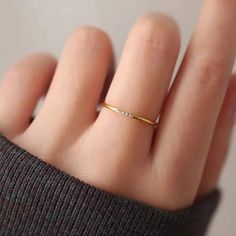 a woman's hand with a gold ring on top of her finger and the bottom half