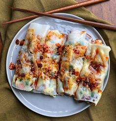 a white plate topped with chinese food next to chopsticks