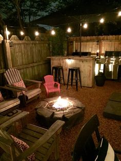 an outdoor fire pit surrounded by chairs and lights