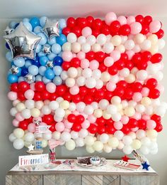 an american flag made out of balloons is displayed on a table in front of a wall