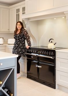 a woman in a black dress standing next to an oven