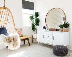 a living room with white furniture and plants in the corner, including a hammock chair