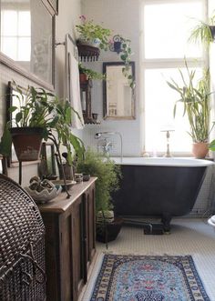 a bathroom with a bathtub, rug and plants on the floor in front of it