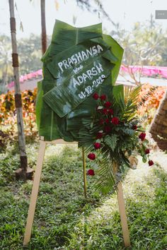 there is a sign that has been placed in the grass with flowers and leaves on it