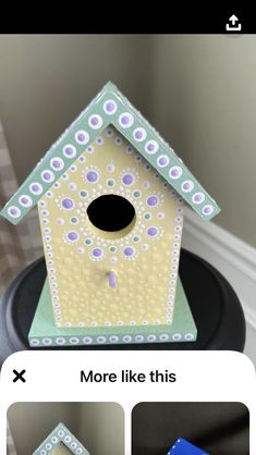 a birdhouse sitting on top of a black table next to a white and green wall