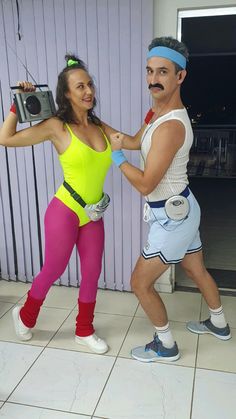 a man and woman dressed in costumes posing for a photo together, one holding a camera