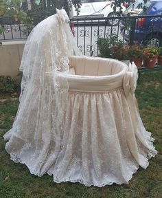 a baby crib with a white cover on it in the grass next to some potted plants